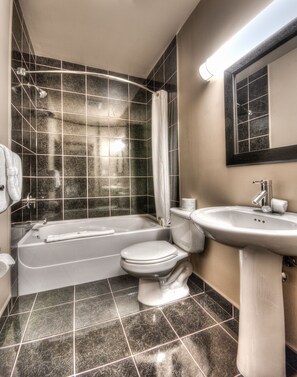 A bathroom with a bathtub, toilet, and sink. - Grand Inn & Residence (Grande Prairie)