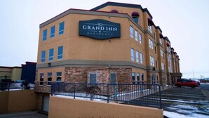 A Grand Inn & Residence building with a brick facade, multiple windows, and a sign indicating its name. - Grand Inn & Residence (Grande Prairie)