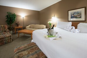 Ett hotellrum med en stor säng, en soffa, ett soffbord, en krukväxt och en inramad tavla på väggen.
