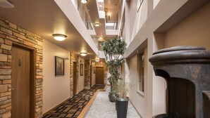 Un couloir d’hôtel avec un mur en pierre, une porte en bois, une plante en pot et une fontaine.