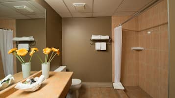 Ein Badezimmer mit beiger Wand, Toilette in Weiß, Waschbecken mit Spiegel und Duschbereich.