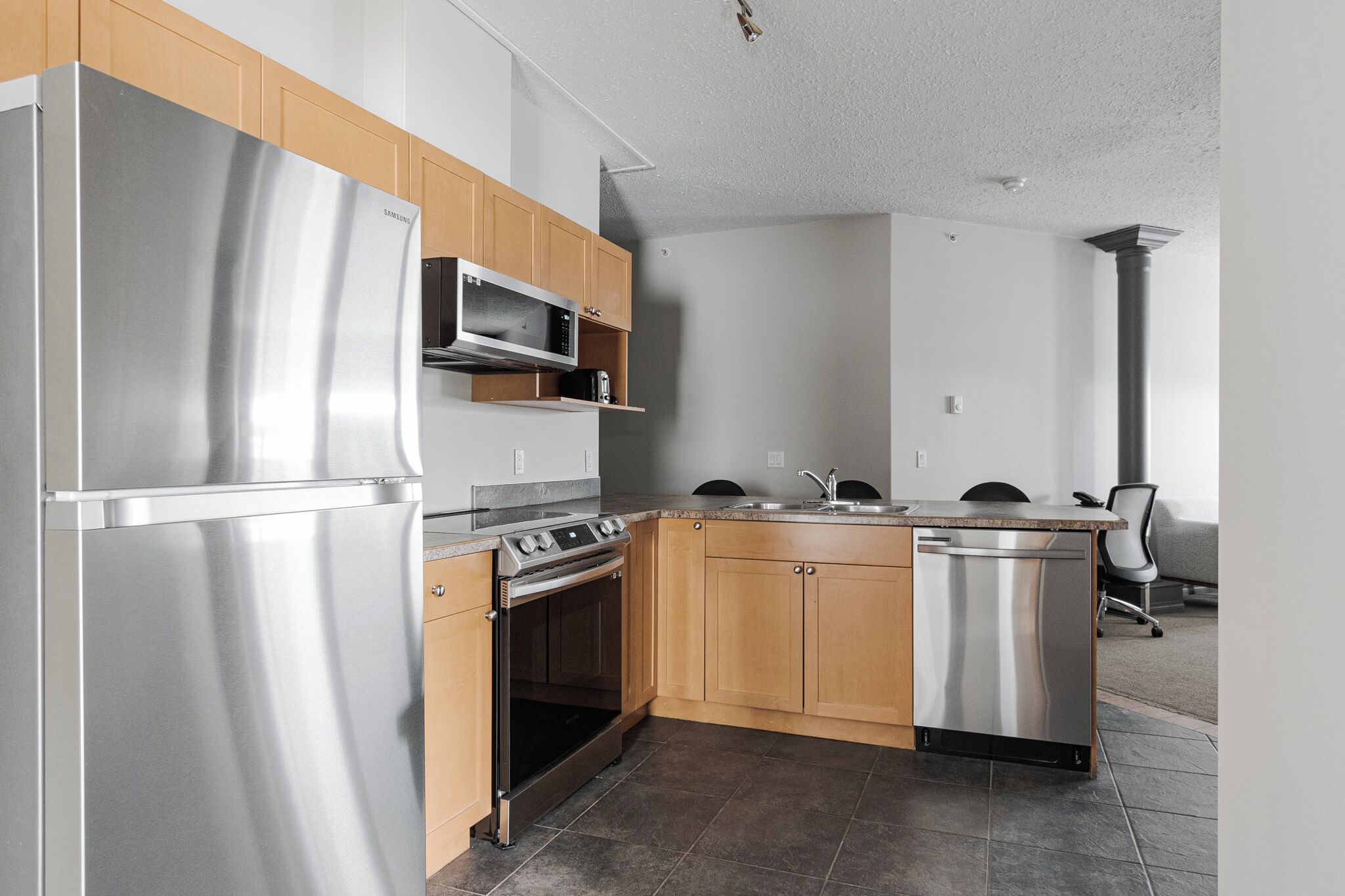 A modern kitchen with stainless steel appliances, wooden cabinets, and a built-in oven.
