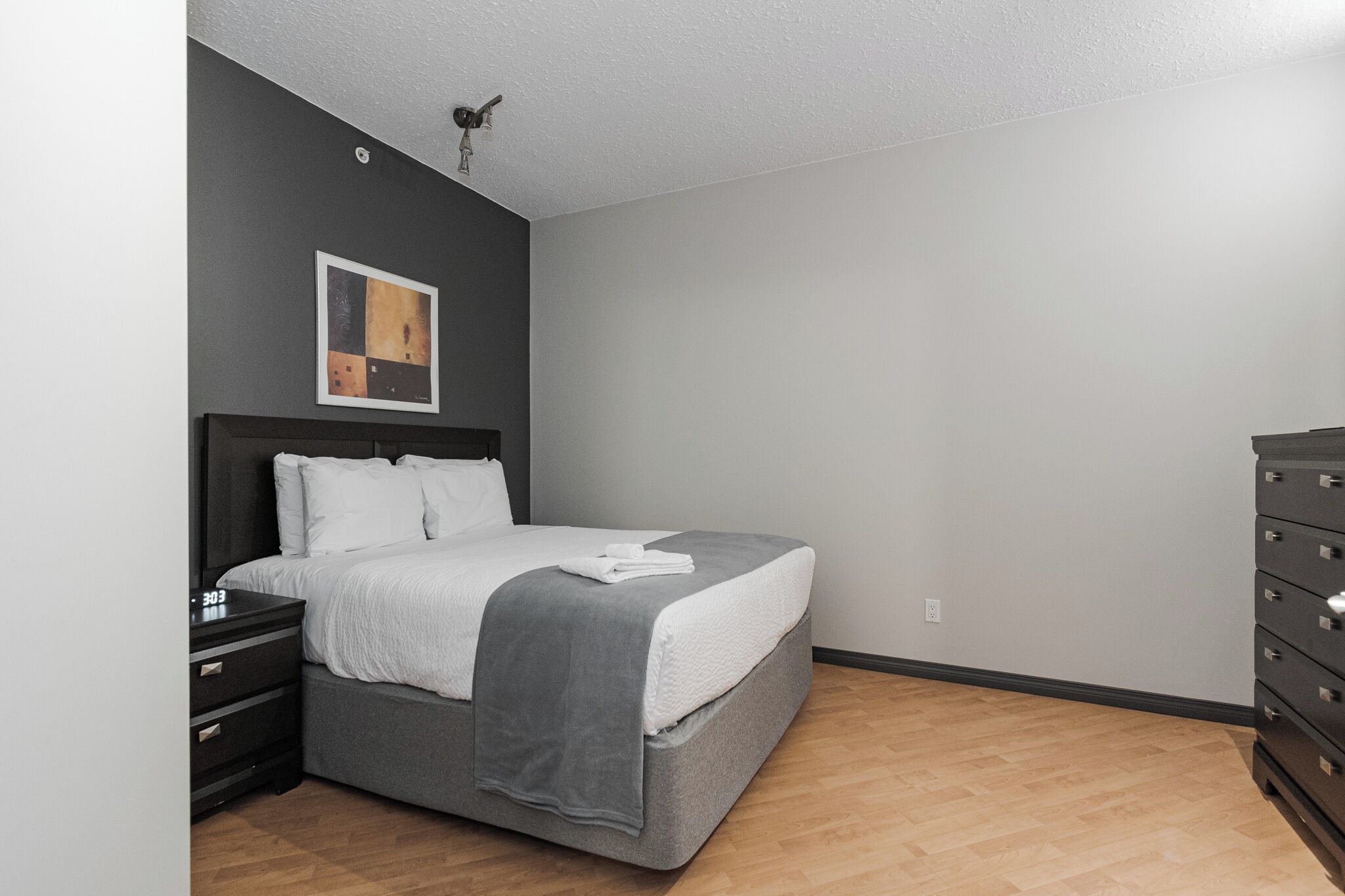 Un dormitorio con cama, mesita de noche, cómoda y ventilador de techo.