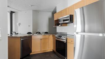 A modern kitchen with wooden cabinets, a stainless steel refrigerator, a built-in microwave, and a dishwasher.