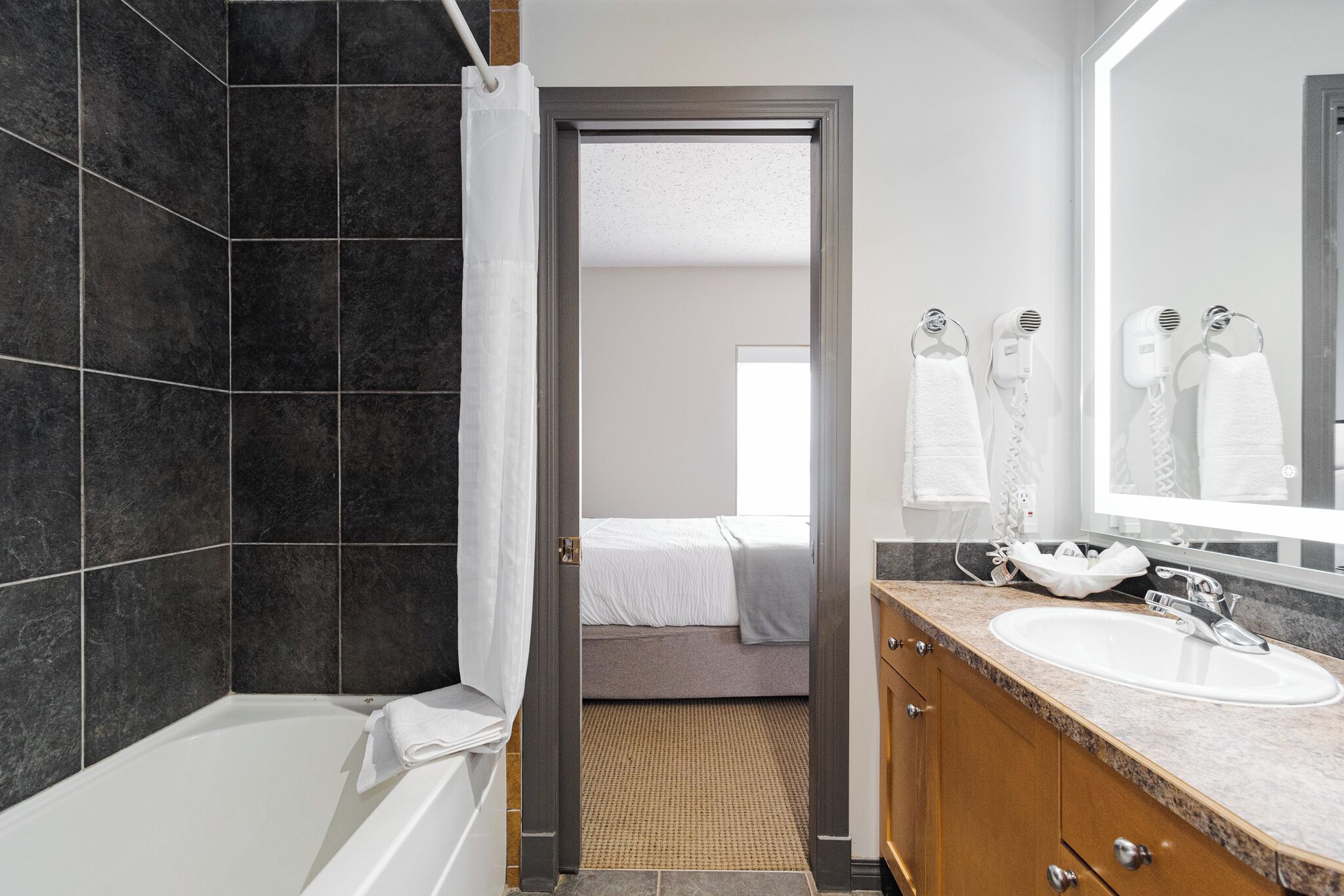 A modern bathroom with a bathtub, a shower, a vanity with a sink, and a mirror.