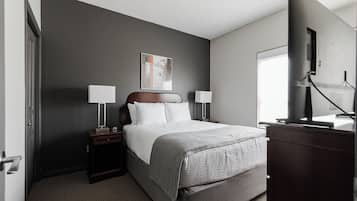 A hotel room with a bed, bedside tables, a TV, and a window.