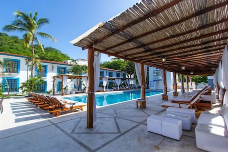 Outdoor pool, pool umbrellas, sun loungers. Hotel Santa Cruz Huatulco