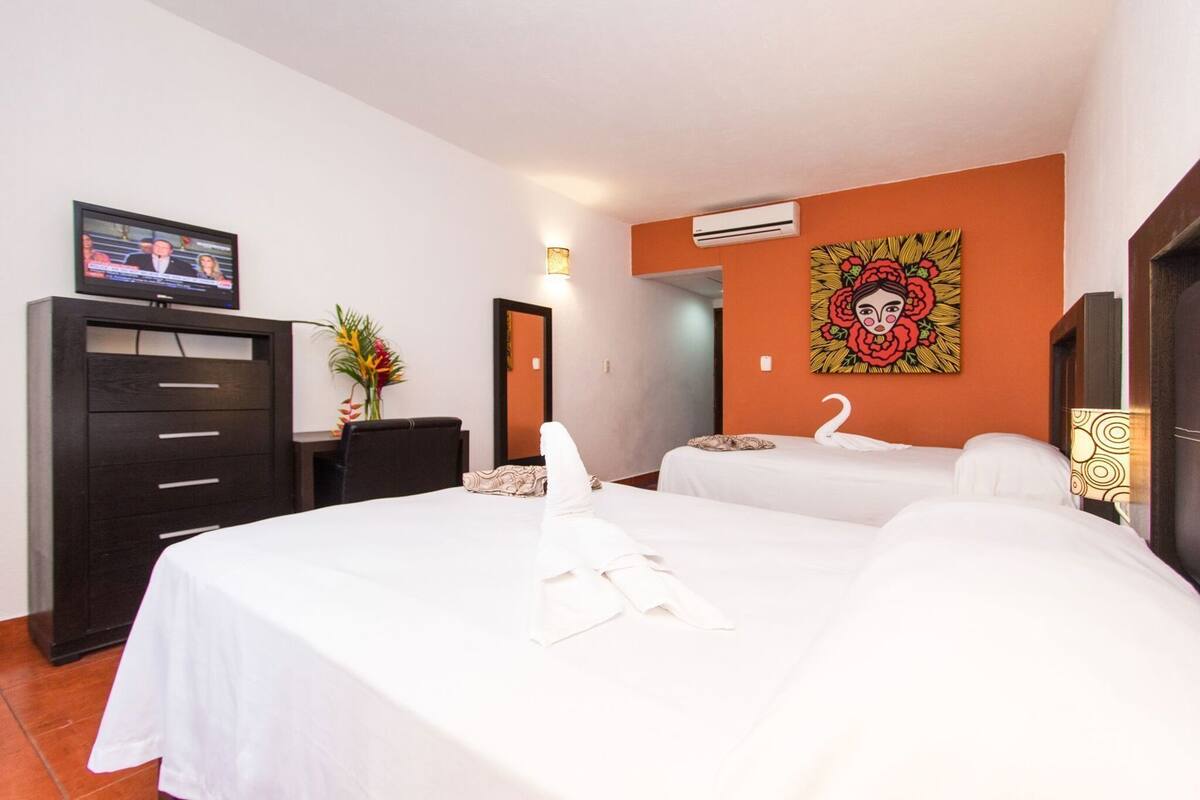 Een hotelkamer met twee bedden, een bureau, een televisie en een schilderij aan de muur.