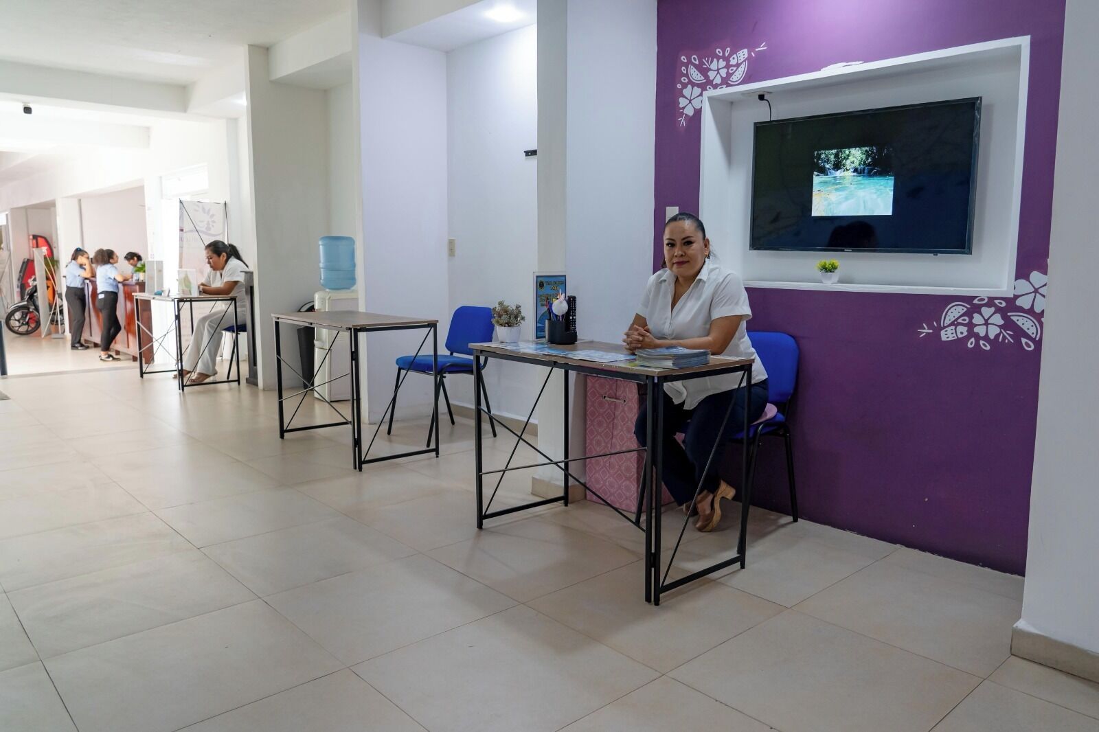 A reception area with a TV mounted on the wall, a reception desk, and several chairs.