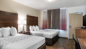 Une chambre d’hôtel avec deux lits, un bureau, une télévision et une porte.