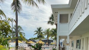 Une cour d’hôtel avec une piscine, des palmiers et des chaises longues.