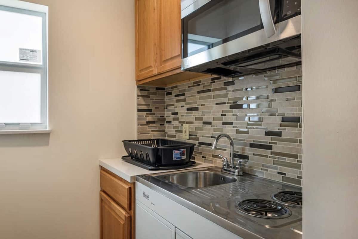 A compact kitchen with a stainless steel sink, a microwave, and a dishwasher.