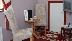 A room with two patterned chairs, a small wooden table with two cups, a television on a stand, and a patterned rug. - Mourneview B&B (Carlingford)