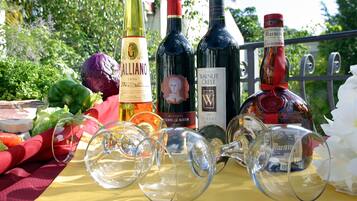 A table with wine bottles and glasses, a red cloth, and some vegetables.