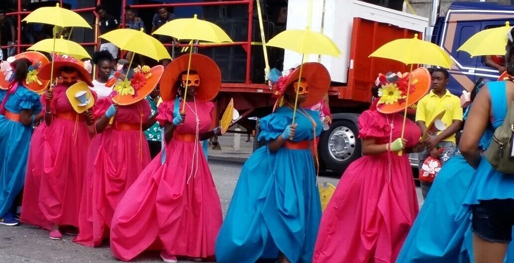 A group of people in colorful costumes with umbrellas.
