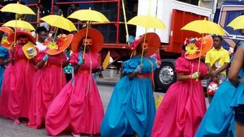 A group of people in colorful costumes with umbrellas.