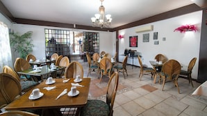 Un comedor con mesas y sillas de madera, una lámpara de araña y vistas al exterior.