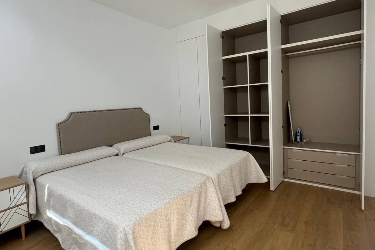 Un dormitorio con cama, mesita de noche y vestidor con estantes.