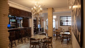 Zona de bar con mostrador, sillas de madera y una araña. Hay un comedor con una mesa y sillas, y un ventanal con vistas.