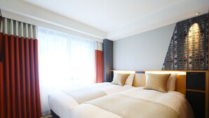 Una habitación de hotel con una cama grande, una mesita de noche y una cortina estampada.