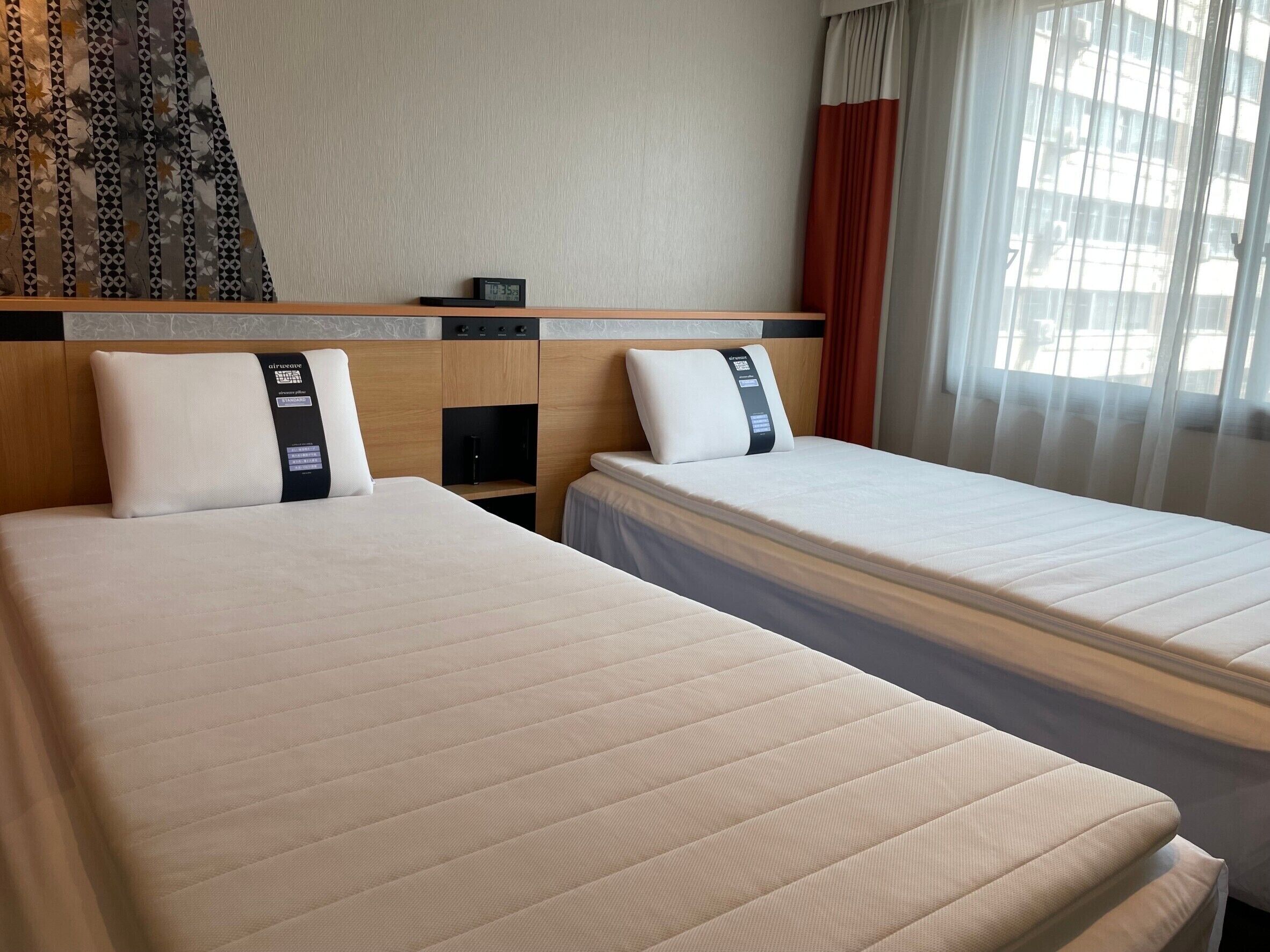 Ein Hotelzimmer mit zwei Betten, einem Kopfteil, einem kleinen Tisch und einer Uhr.