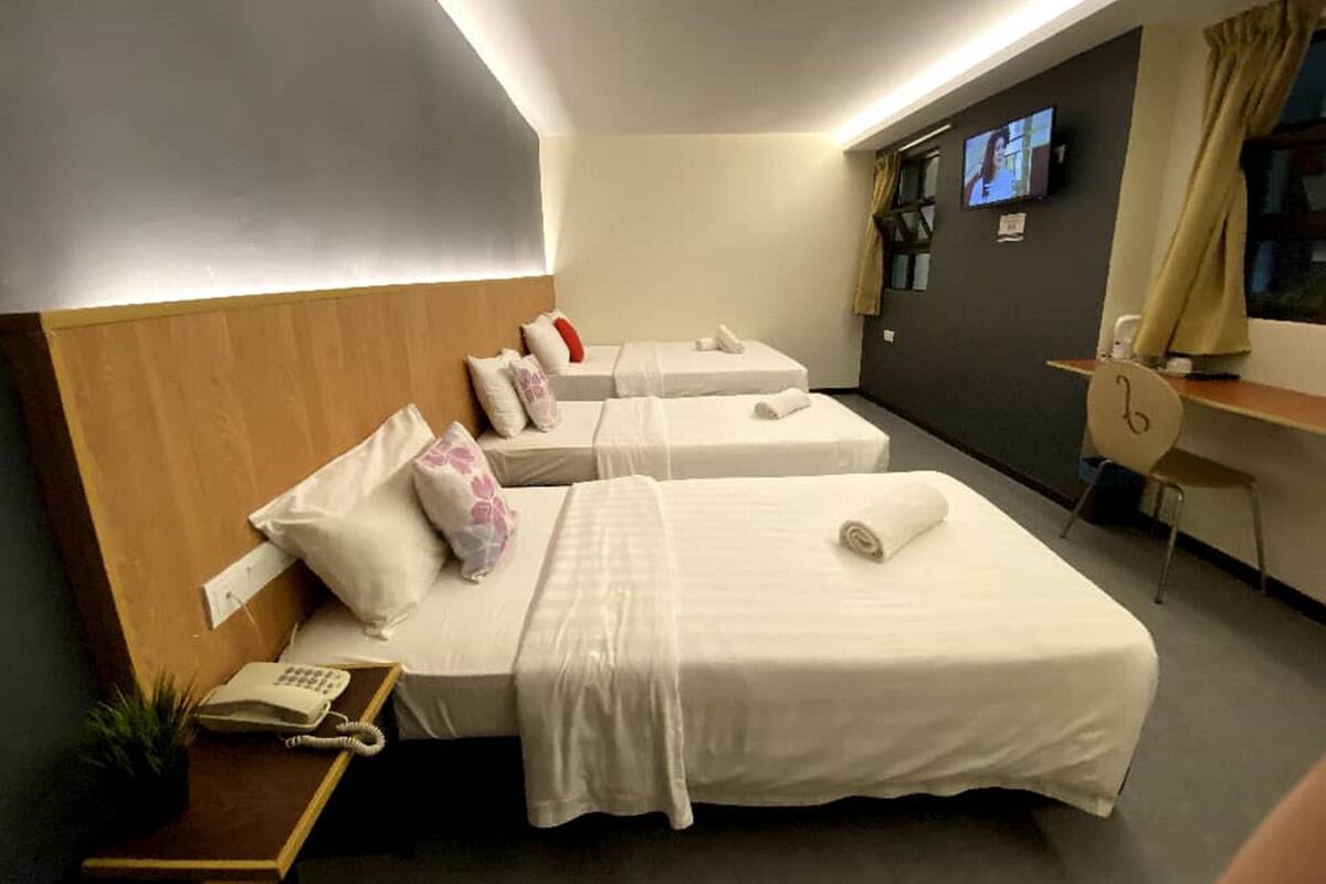 A hotel room with two beds, a desk, a TV, and a phone.