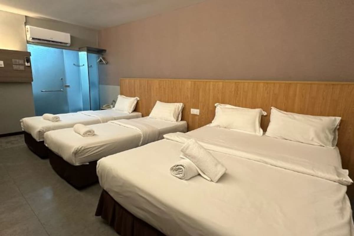 A hotel room with three beds, a wooden headboard, and a blue wardrobe.