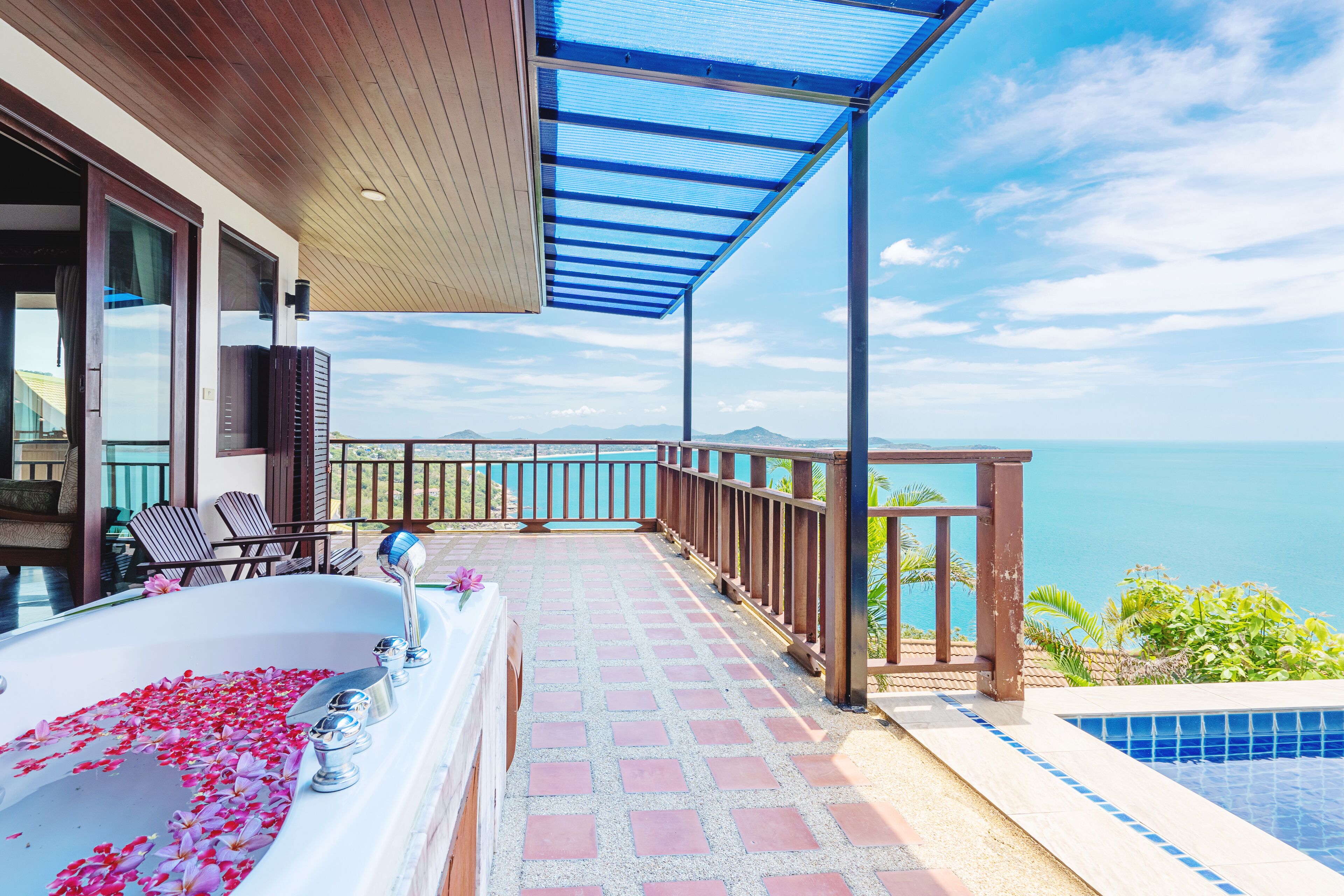Ein Balkon mit Meerblick, eine Badewanne mit Rosenblüten und ein Pool.