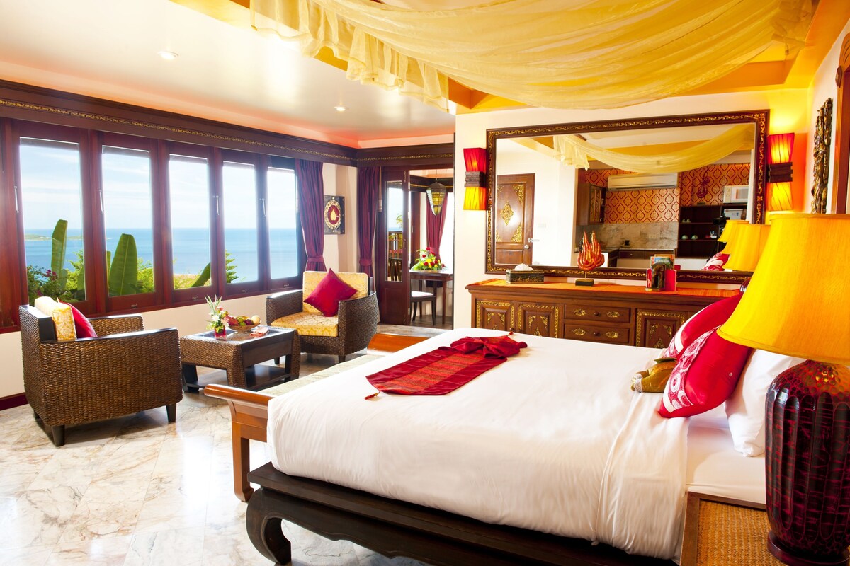 Une chambre d’hôtel spacieuse avec un grand lit, un coin salon avec vue et un espace repas séparé.