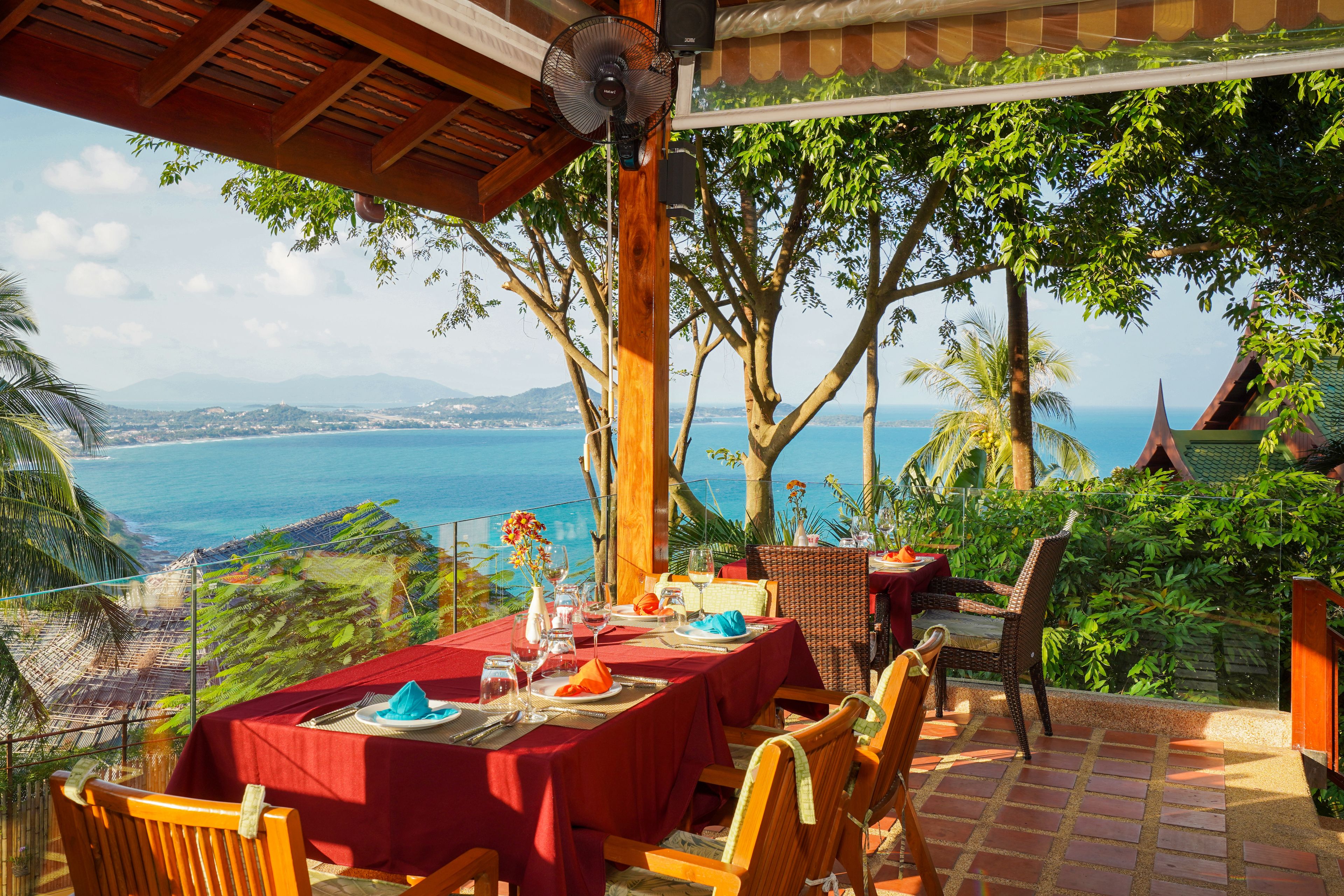A table set for dining with a view of the ocean and hills.