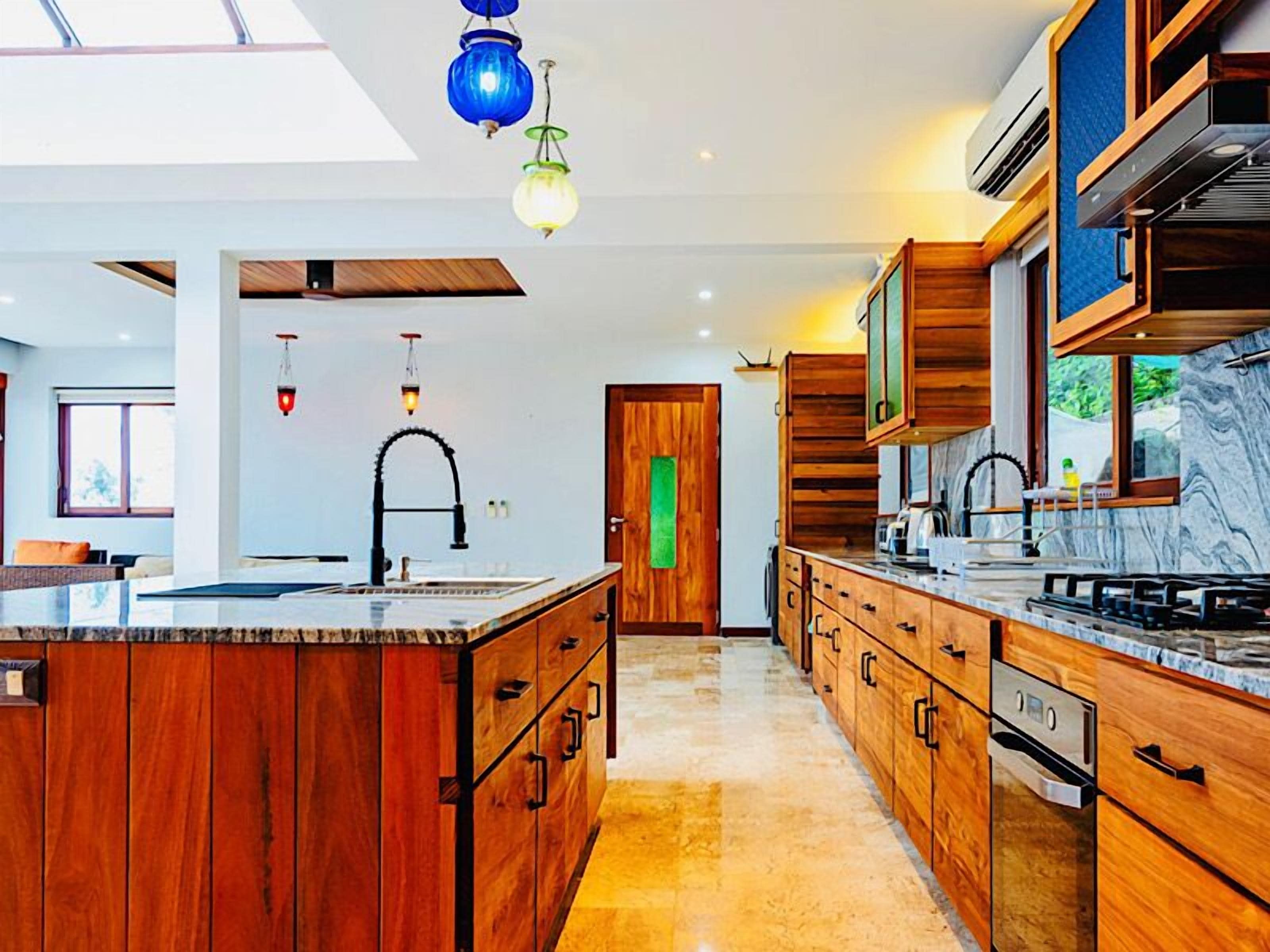 Una cocina moderna con armarios de madera, una isla central y un amplio ventanal que proporciona luz natural.