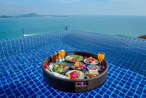 Una mesa de comedor junto a la piscina con vista al mar.