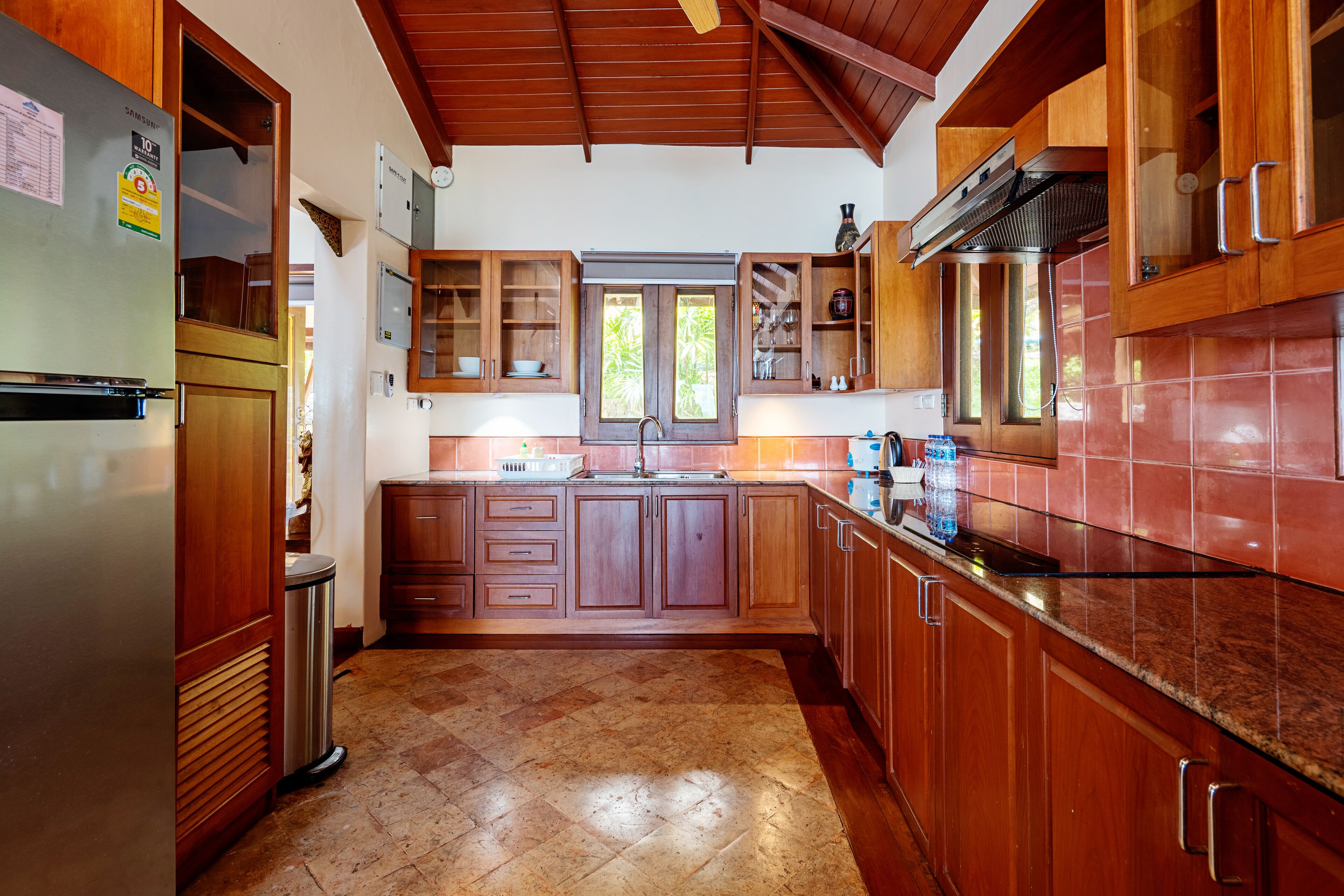 A kitchen with wooden cabinets, a stainless steel refrigerator, and a tiled backsplash.