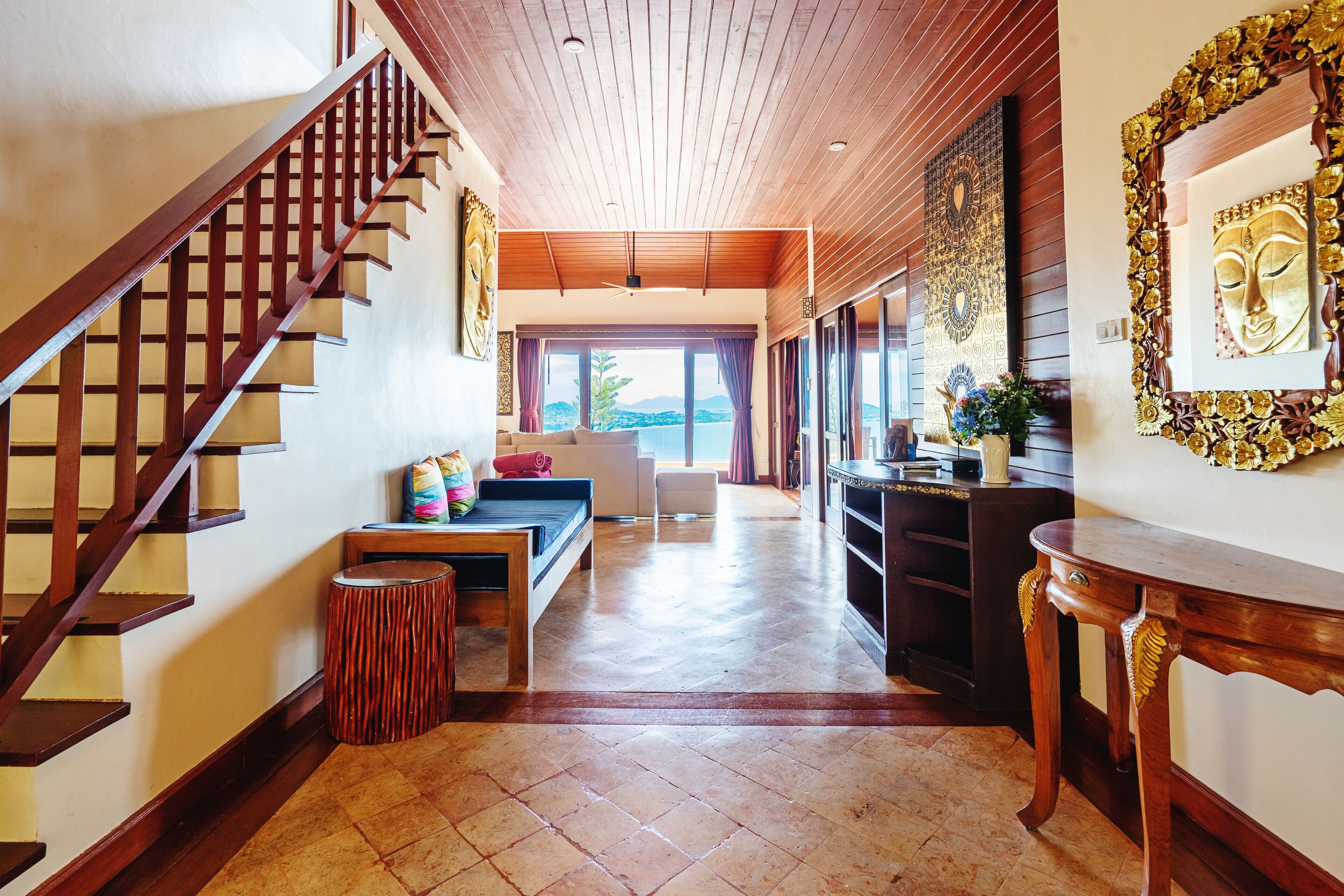 A spacious hallway with a wooden staircase, a bench, and a dining area with a view.