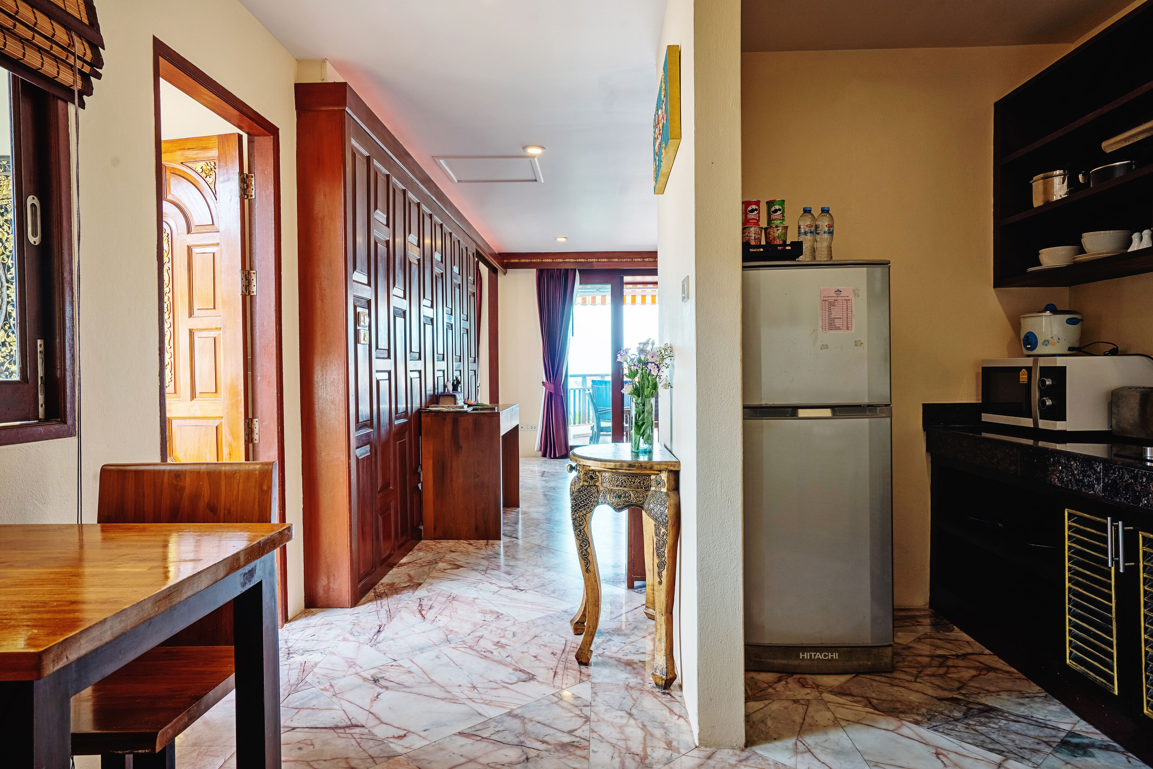 A kitchen with a marble floor, a refrigerator, and a microwave.