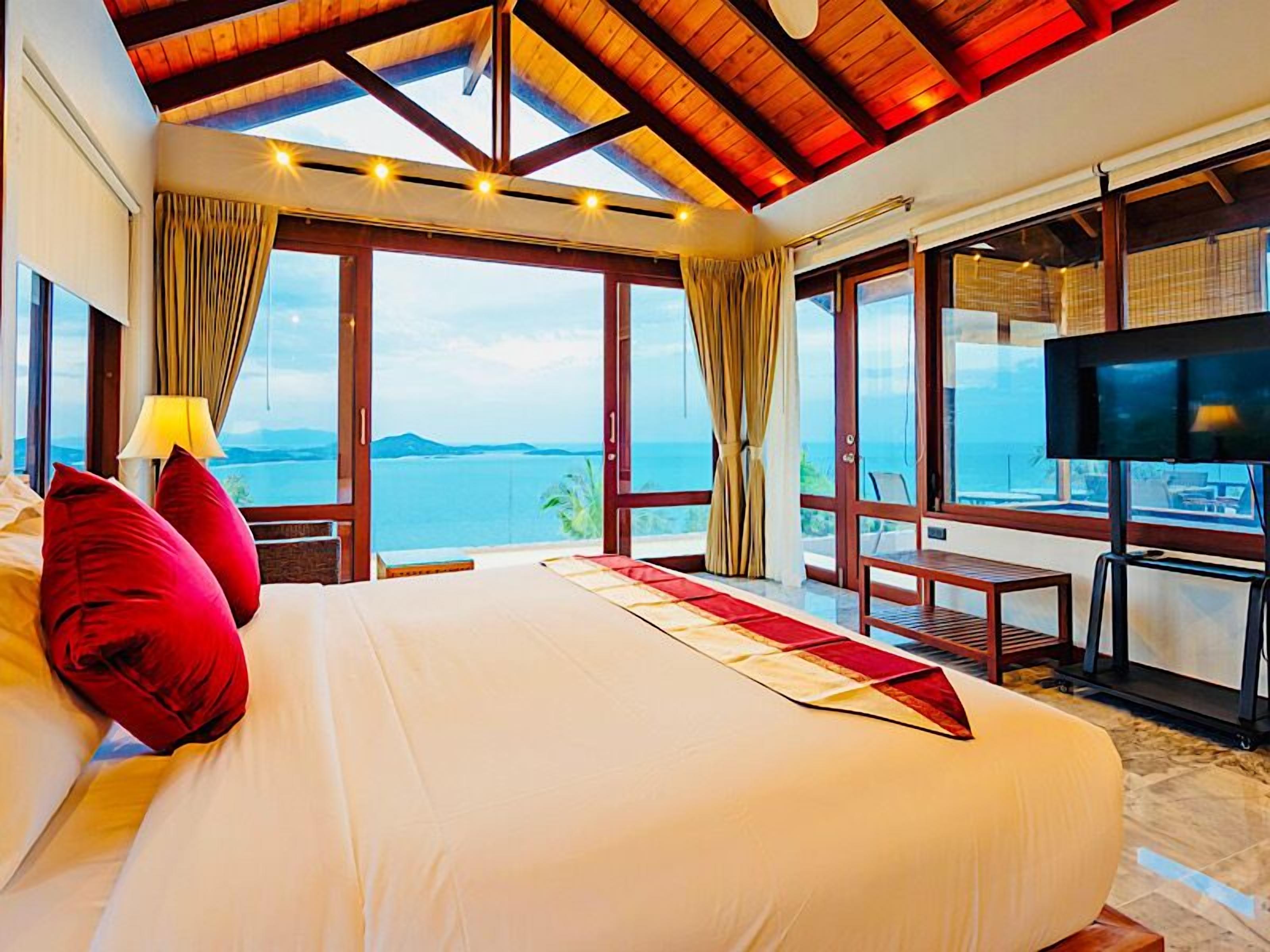 Habitación de hotel con una cama grande, un televisor y un balcón con vista al mar.