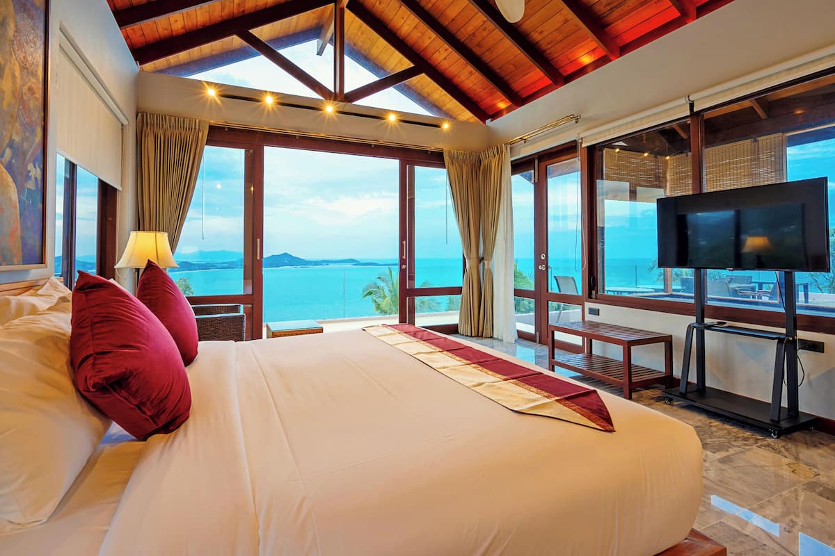 Een groot bed met uitzicht op zee, een televisie en een loopband.