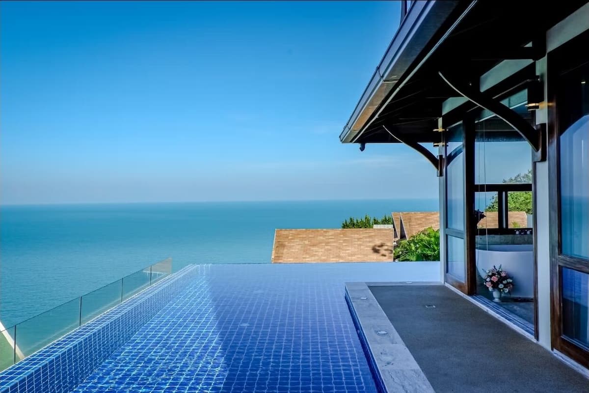 Een zwembad zonder rand met een helder uitzicht op de oceaan, een glazen balkon en een modern architectuurontwerp.