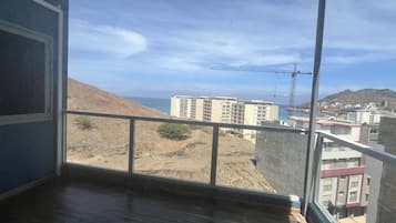 Una habitación con un ventanal grande que da a una obra en construcción, edificios y un paisaje montañoso.