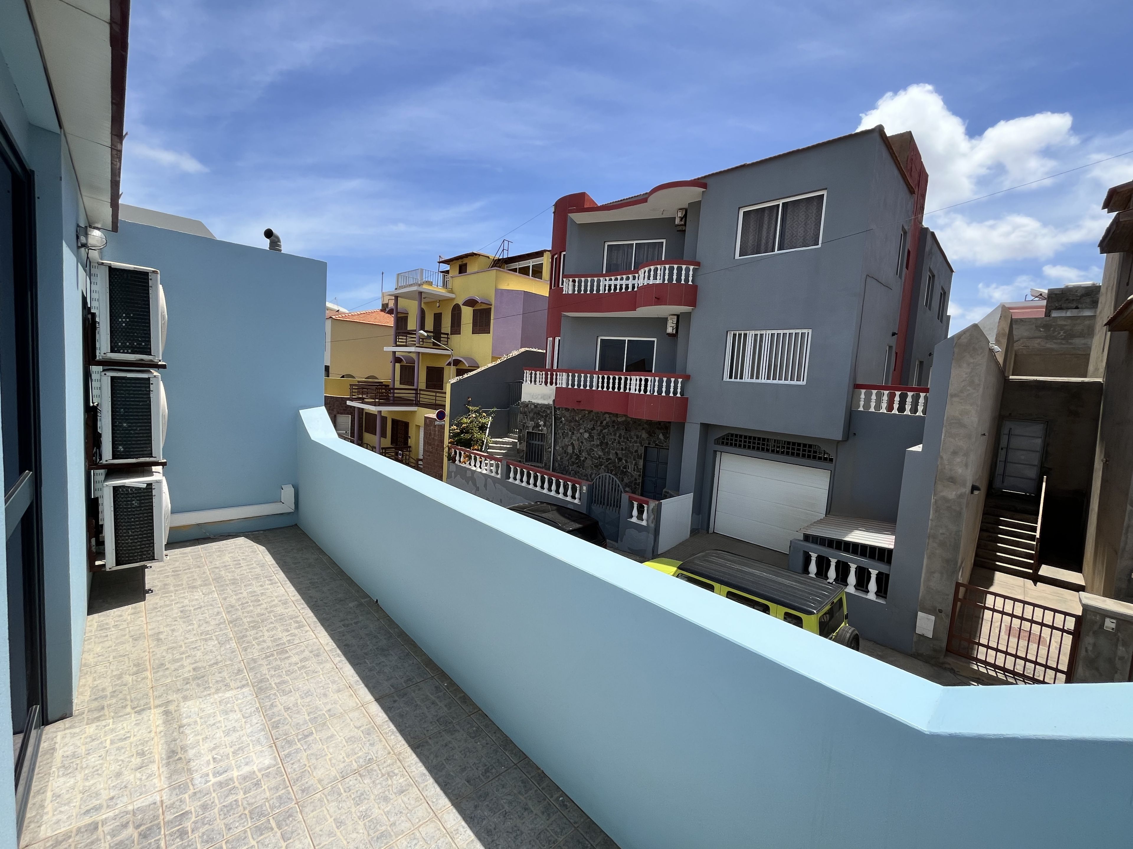 Zona residencial com edifícios altos, portão fechado e céu limpo.