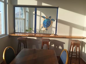 En matplats med ett träbord och stolar, ett stort fönster och en dekorativ väggdekoration i form av en sköldpadda.