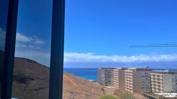 A coastal view with a construction site, buildings, and a crane.