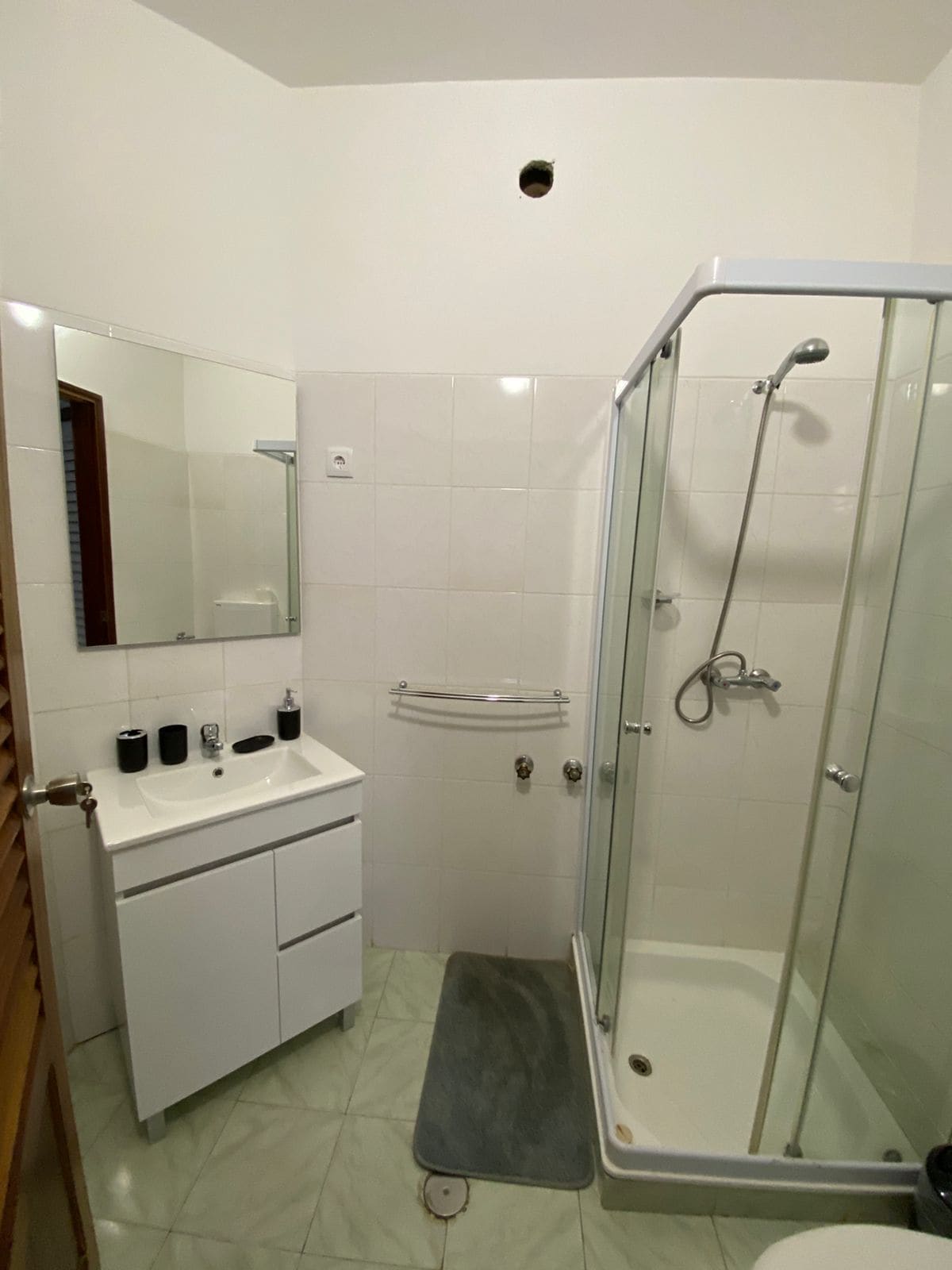 A bathroom with a glass-enclosed shower, a white sink, and a mirror above the sink.