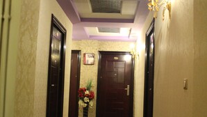 A hallway with a polished floor, dark doors, and a wall-mounted light fixture. - Hotel Adria (Pristina)