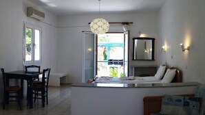 A compact kitchen with a dining area, a small island, and a balcony with a view. - Zeus Hotel (Samos)