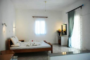 Un dormitorio con cama de madera, una mesita de noche, un espejo y una ventana con cortinas.