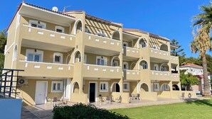 A multi-story hotel with balconies, outdoor seating, and a well-maintained lawn. - Zeus Hotel (Samos)