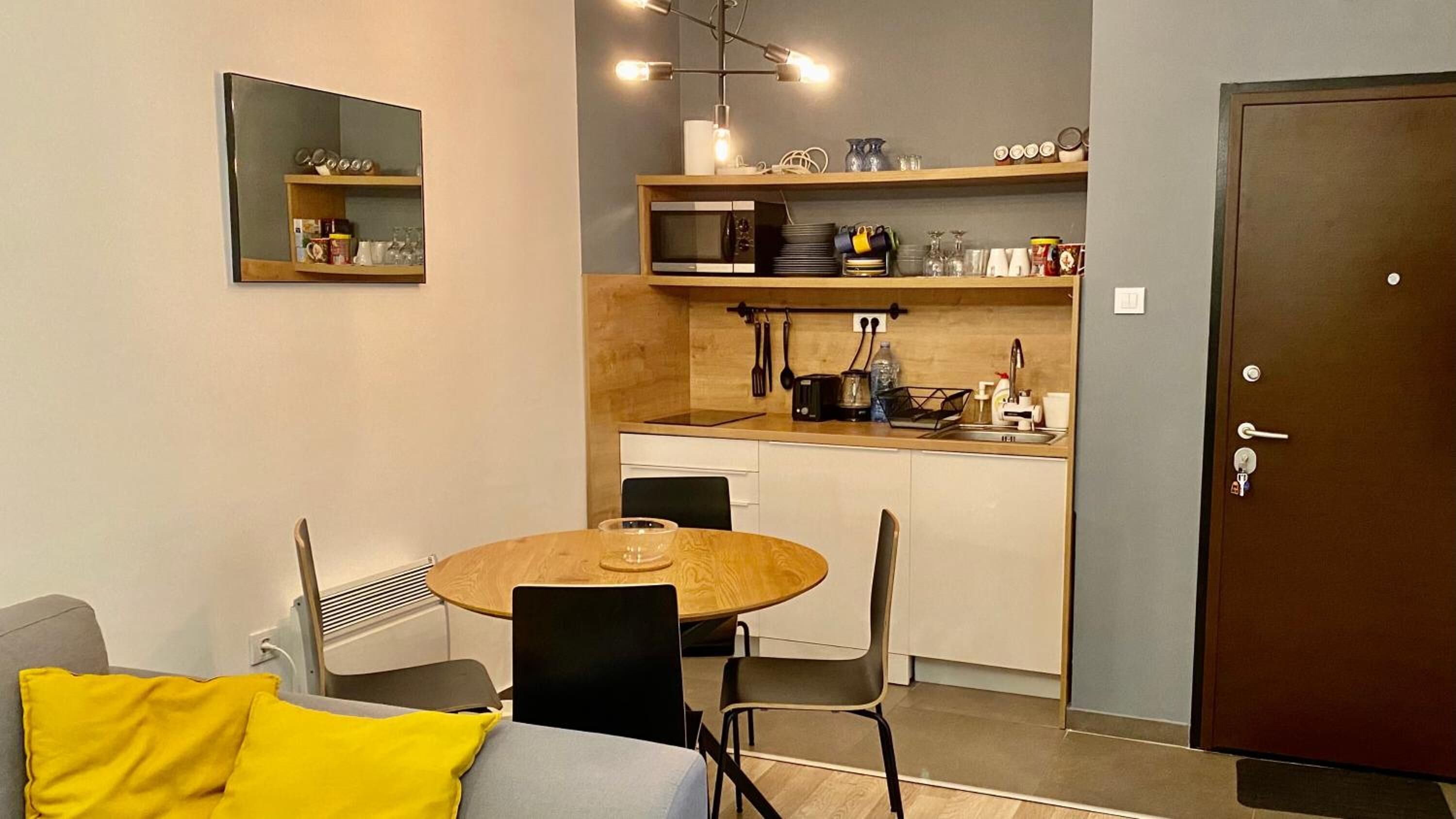 Un espacio habitable compacto con una mesa de comedor, sillas, un sofá, una kitchenette y una puerta.