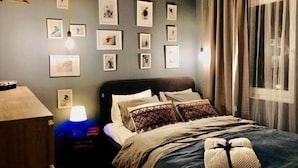 A neatly arranged bedroom with a bed, bedside table, lamp, and wall-mounted artwork. - JollyKop (Raška)