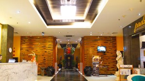 A hotel lobby with a checkered floor, a reception desk, a TV, and a statue. - Puri Denpasar Hotel (Jakarta)